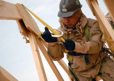071221-N-3857R-007 AR RAMADI, Iraq (Dec. 21, 2007) Builder 3rd Class Adam Turbeville, assigned to Naval Mobile Construction Battalion (NMCB) 1, connects his safety harness to a truss while working on the construction of a fellowship hall at Camp Ramadi. The hall will be used to host conferences, celebrations, and worship services, and will also serve as a place for service members to relax. NMCB 1 is deployed to several locations in the Middle East, Afghanistan and Micronesia providing responsive construction support to U.S. military operations. NMCB 1 is also part of nearly 1,100 Sailors and Marines supporting critical construction efforts in the Al Anbar Province of Iraq. U.S. Navy photo by Mass Communication Specialist 2nd Class Chad Runge (Released)