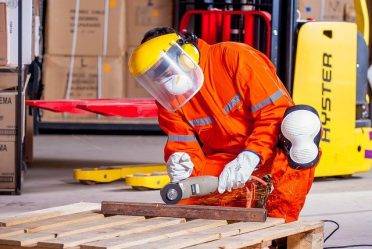 Worker in protective gear welding a piece of metal.