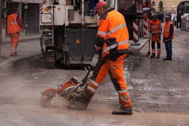 construction worker cutting into a road with a cement saw.