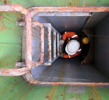 a man with self contained breathing apparatus and lifeline is climbing on the ladder into an enclosed space on cargo ship for training and drill during PSC CIC 2019 - concentrate inspection campaigns