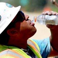 Construction worker drinking water on a hot day.