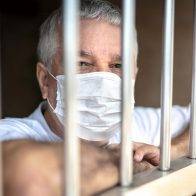 Man wearing a mask behind bars.
