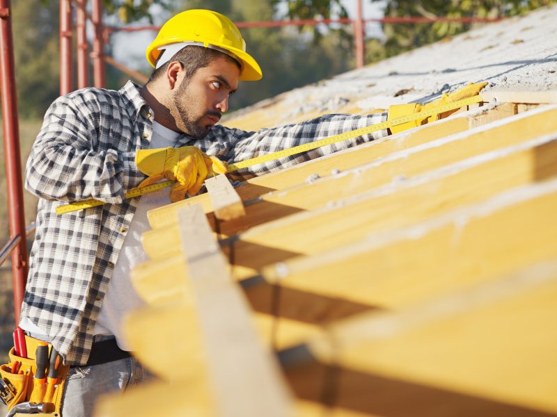 graphicstock-latin-american-construction-worker-on-house-roof-with-measuring-tape-copy-space_SQwn0w9DW-e1571142545833